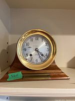 Front view of clock on wooden base showing brass bezel and dial