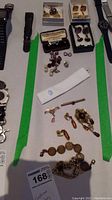 Wide view showing assorted cufflinks, cufflink box, tie clip, brooch, earrings and bracelet
