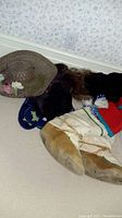 Photo of various hats and footwear arranged on floor against wall, showing full set of hats and one mukluk boot