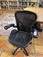 Front view of black mesh seat and back with armrests and five-star caster base