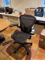 Front view of chair showing mesh seat, back and adjustable armrests