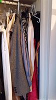Rack view showing beige skirt, tweed blazer, black coat, and striped blouse