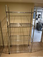 Front view of tall metal bakers rack shelving unit with four wire shelves.