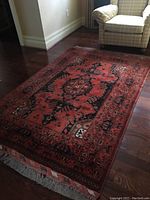 Full rug displayed on hardwood floor beneath armchair
