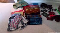 Photo of scarves, clothing items, wallets, belt, and sunglasses arranged on carpet showing the lot's contents