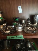 Multiple silver plated items displayed on wooden shelf including creamer, sugar bowl, and serving pieces