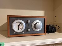 Front view showing wooden cabinet, analog clock and radio controls