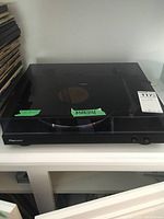 Closed Pioneer PL-30-K turntable with dust cover on shelf near vinyl records