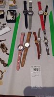 Overview photo showing all nine watches laid out on a table with other small jewelry items surrounding.