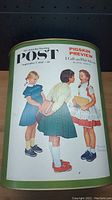 Metal tin depicting Norman Rockwell style illustration of three girls from a vintage Saturday Evening Post cover, dated September 7, 1957.