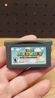 Photo of front label of Super Mario World Game Boy Advance cartridge showing the title and ratings.
