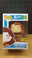 Front view of sealed Funko Pop box showing Dark Phoenix figure inside with Hot Topic exclusive sticker.