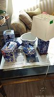 Top view of cobalt blue ceramic items including fish, jars, bowl, lamp, bird figurine displayed on table