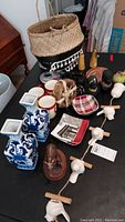Overview of multiple items on black surface including vases, mugs, basket, camel figurine, and bird decoration