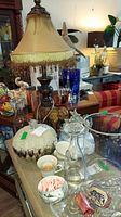 Overview of elephant lamp, trinket boxes, Lenox tea cups, glass basket, and additional glass items on table