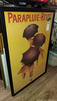 Full view of main Parapluie-Revel framed art print showing yellow background and umbrella figures