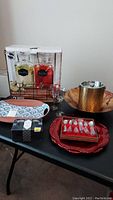 Photo showing the full setup of party serving items on table, including plated chargers, beverage dispensers in box, ice bucket, and small kitchenware items.