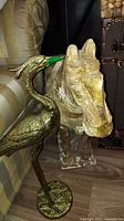 Resin horse statue next to brass metal bird figurine showing front and side views
