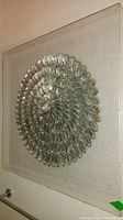 Side angled view showing the Lucite box frame and iridescent spiral shell arrangement on fabric backing.