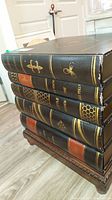 Side view showing book spines styled drawers with titles and gold accents.