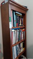 Front view of wood bookcase filled with books and items, shows condition and shelf arrangement.