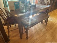 Dining table with two benches and two chairs around it, table top shows wear.