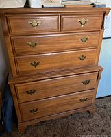Front view of the wooden dresser showing six drawers with brass-tone handles.
