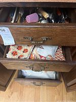 Top view of four wooden drawers, with visible kitchen towels in two drawers and partial view of utensils in the top drawer.