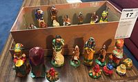 Photo of multiple Native American figurines displayed on table and inside a cardboard box for sale as a lot of 20.
