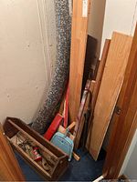 Photo showing scrap wood pieces leaning against basement wall alongside an old toolbox and household items.