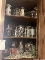 Multiple shelves filled with vintage beer pint glasses and mugs featuring sports themes and other graphics.