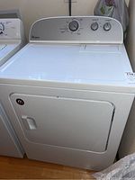 Front view of Whirlpool white clothes dryer showing door and control panel with three control knobs.