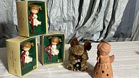 Five Christmas angel figurines displayed including three in boxes, a plush moose Christmas angel and a larger ceramic angel.