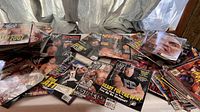 Wide view of multiple stacks of wrestling magazines with colorful covers featuring WWE wrestlers.