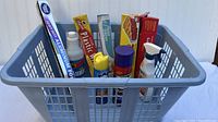 Gray plastic laundry basket with household cleaning and kitchen items