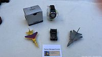 Timex Iron Man watch new in box displayed alongside three Matchbox style toy airplanes (yellow, black, and gray).
