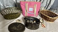Overview photo showing the two decorative baskets, the small pink handbag, and the round tin container filled with buttons.