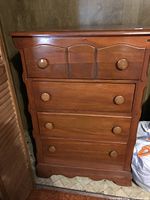 Front view of the vintage pine chest of drawers showing four drawers with round wooden knobs and decorative top drawer.