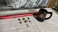Photo showing black beer stein with United States Marine Corps emblem and pins laid out on white surface with two red rods.