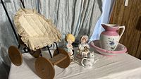 Full lot showing vintage doll baby carriage with cream quilted seat, ceramic pitcher and bowl, ceramic child figurines, ceramic cat creamer, and animal statues