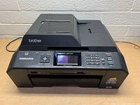 Front view of the Brother MFC-J5910DW printer/scanner showing control panel, LCD display, numeric keypad, and input/output trays.