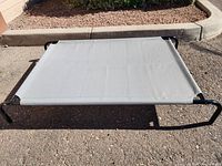 Full view of the grey fabric elevated pet bed on black metal frame, showing rectangular shape and fabric tension.