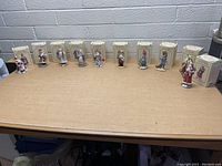 Wide shot of all 11 figurines displayed on table with boxes behind them