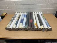 Top view of 15 cylindrical tubes containing new art prints, showing tube ends and some labels.