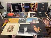 Top-down view of 20 vinyl records in sleeves featuring various artists including Elton John, Neil Diamond, and others.