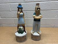 Front view of both vintage hippie and flower child whiskey decanters with cork stoppers on top.