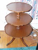 Front-right angle view of the 3 tiered wooden dumb waiter showing the scalloped edges and claw feet base.