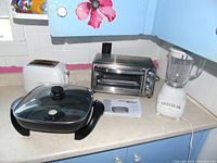 Full view of all four appliances on kitchen counter including toaster oven, toaster, electric skillet, and blender