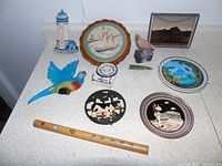 Full view of souvenirs including decorative plates, wooden bird figure, flute, small stones, and ceramic items.
