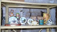 Wide shot of all items on metal shelf showing mugs, figurines, clock, bookends, and pitcher.